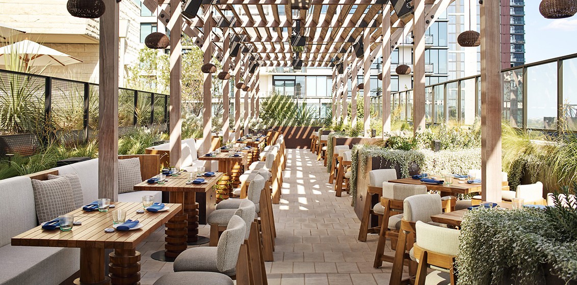 The watr rooftop restaurant at 1 Hotel Austin, with dining room seating overlooking the pool deck and Lady Bird Lake.