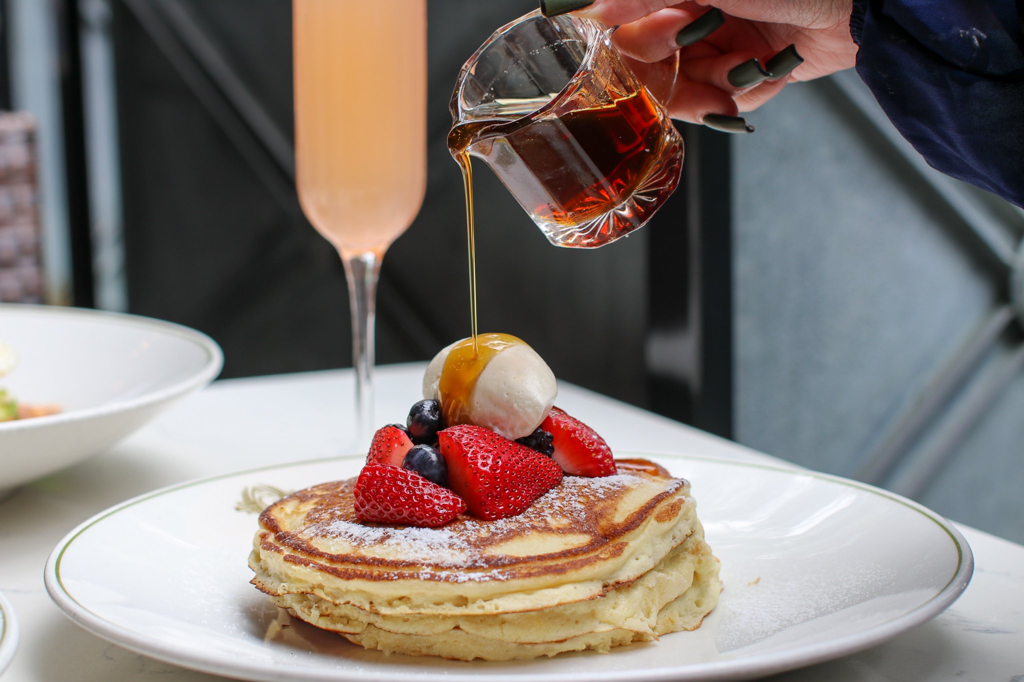The lemon ricotta pancakes at The Gage, syrup going on at the table