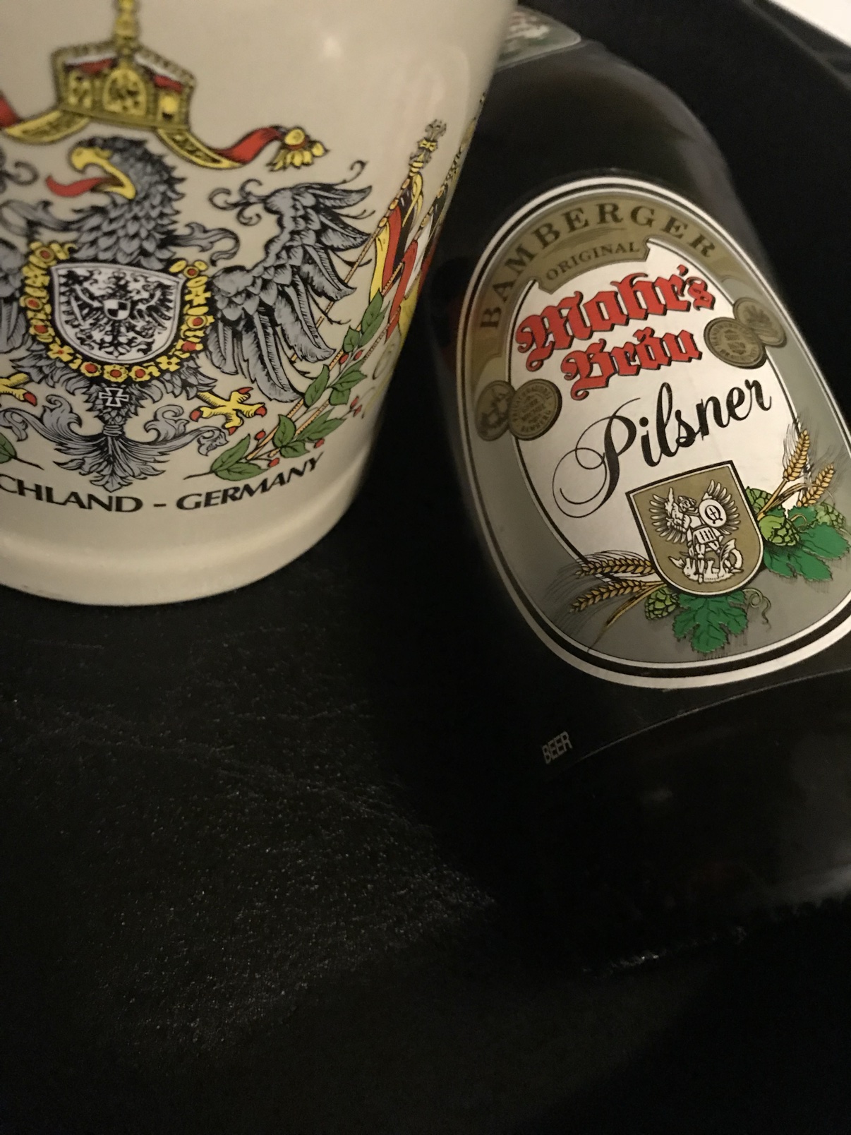 A bottle of Mahr's Bräu Pilsner beside a ceramic German stein painted with the imperial eagle crest.