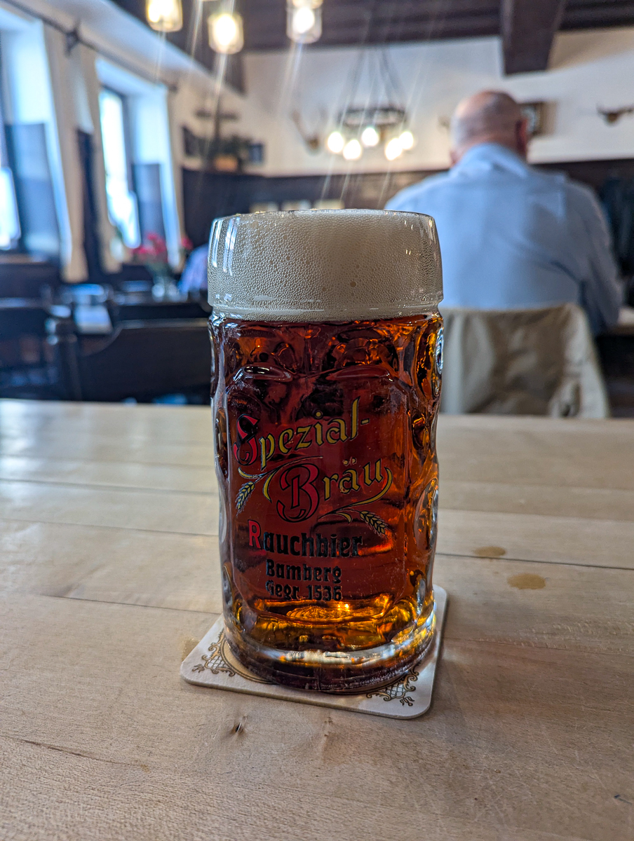 A dimpled Maß of amber Spezial Rauchbier, labeled Spezial-Bräu Bamberg, on a wooden table inside the Brauerei Spezial tavern.
