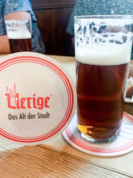 A fresh Uerige Alt in the classic stange glass with a thick foam head, served on a branded Uerige coaster.