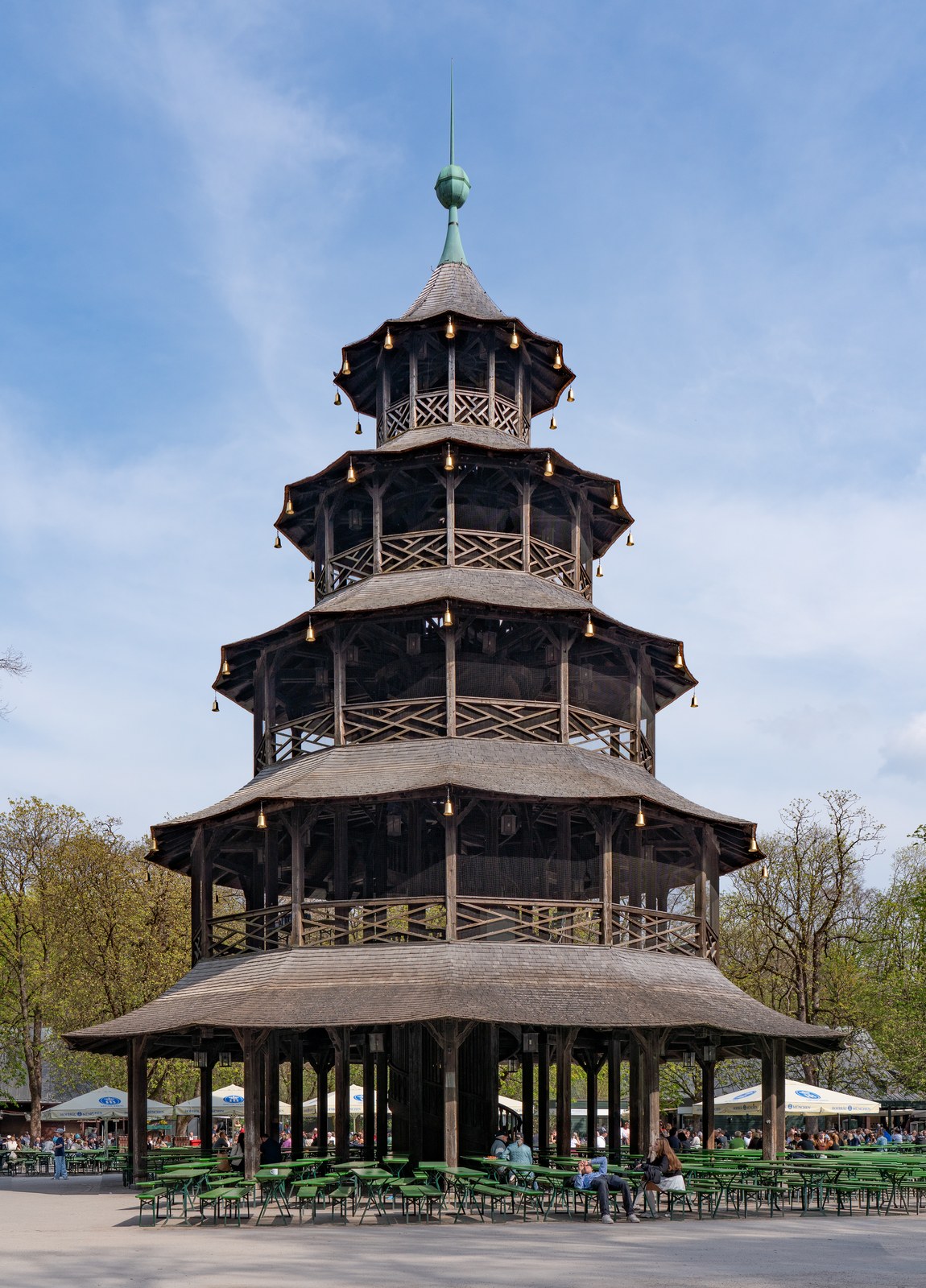 The wooden Chinese Tower pagoda surrounded by beer garden tables and umbrellas in Munich's Englischer Garten.