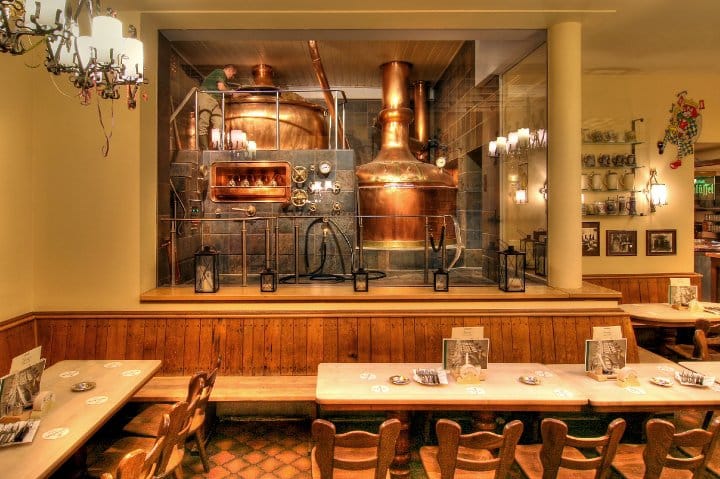 The dining room of Hausbrauerei Zum Schlüssel in Düsseldorf with the copper brew kettles visible behind glass.