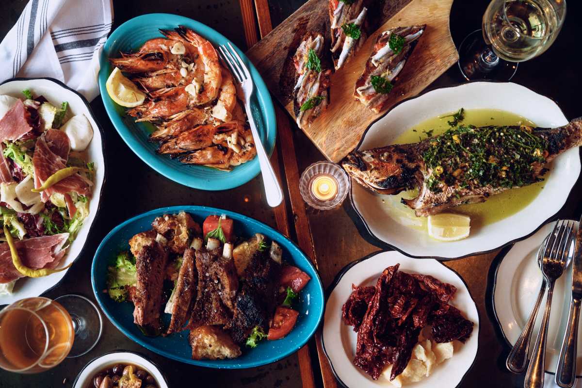 A table spread at Evviva, New Orleans: grilled shrimp, herb-roasted fish, anchovy toasts