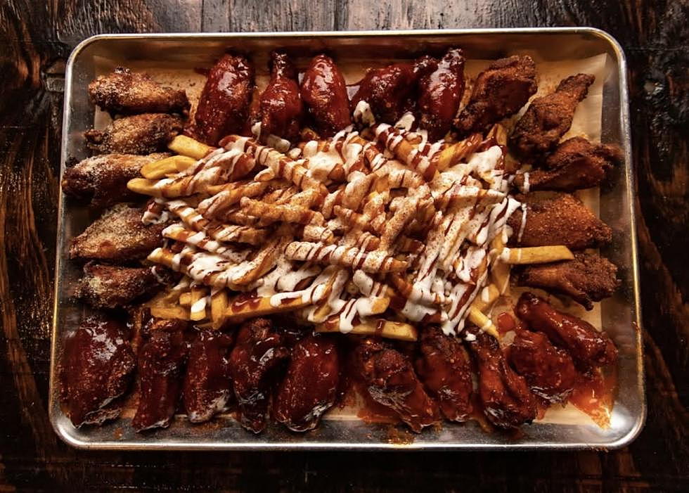 A tray of KOK wings in multiple flavas with seasoned fries drizzled in sauce