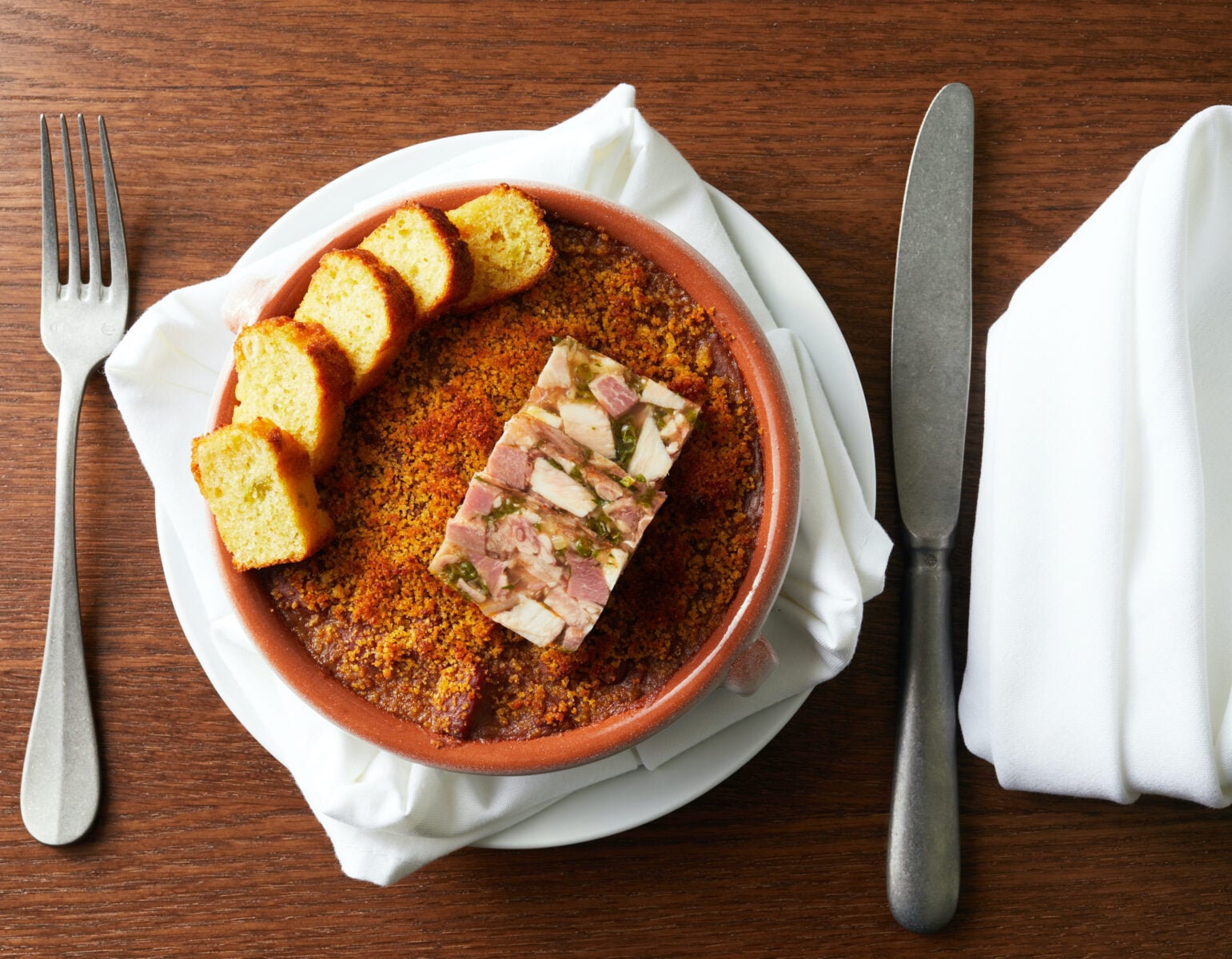 Chicken Bon Femme served family-style at MaMou in New Orleans — a rustic roasted chicken dish with golden potatoes and sauce on a dark wood table.
