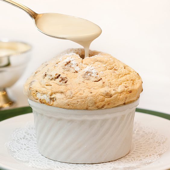 A close-up of a sauced seafood dish from the tasting menu at Commander's Palace in New Orleans, rich and glossy with fresh herbs on a white plate.