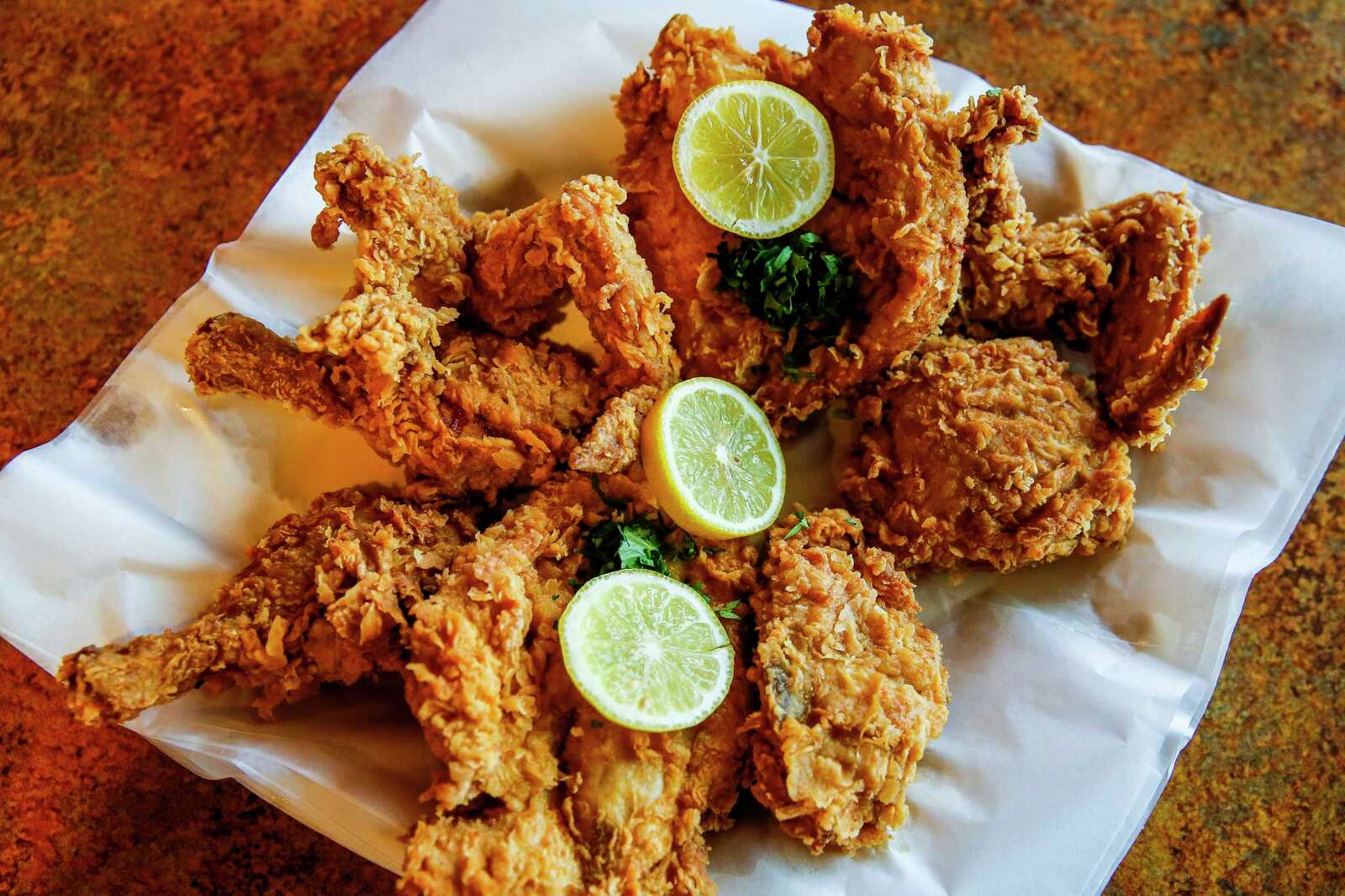 A crispy fried shrimp po'boy at Crabby Jack's in New Orleans, golden shrimp, tomato and lettuce in a soft roll with fries on a checkered paper tray.