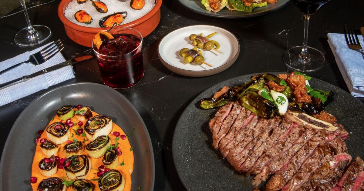 An overhead spread of Basque-inspired dishes at Dolfy's in New Orleans — wood-fired plates, pintxos and small bites arranged across a dark table.