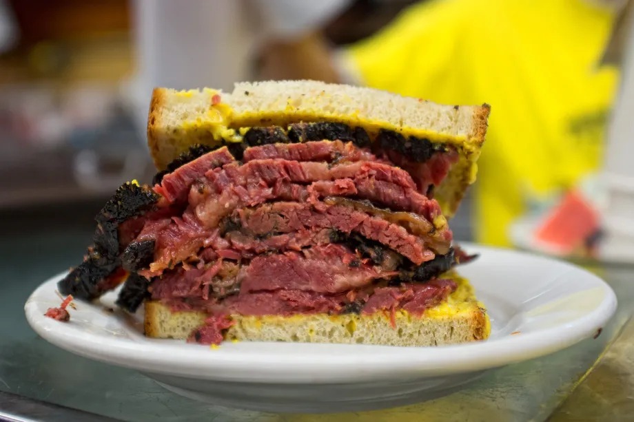 Thick cross-section of Katz's hand-carved pastrami sandwich on rye with mustard at the counter