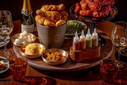 Korean fried chicken spread with bucket, glazed wings, sauces, banchan, and Champagne