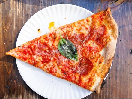 A whole burrata melting over a slice at L'Industrie Pizzeria in Williamsburg, Brooklyn, the top-ranked must-eat spot in New York.