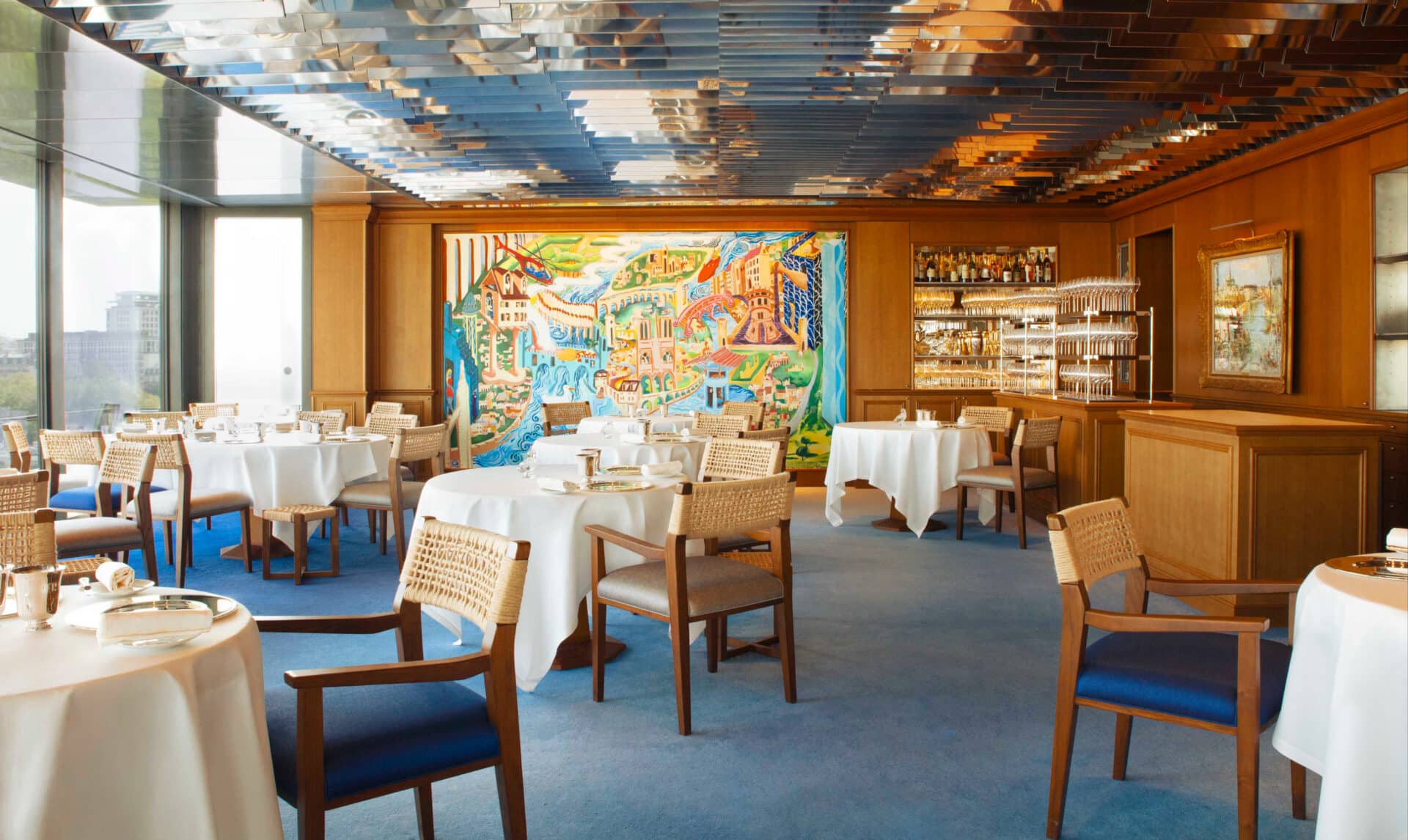 The dining room at La Tour d'Argent, Paris, with its Paris mural and set tables.
