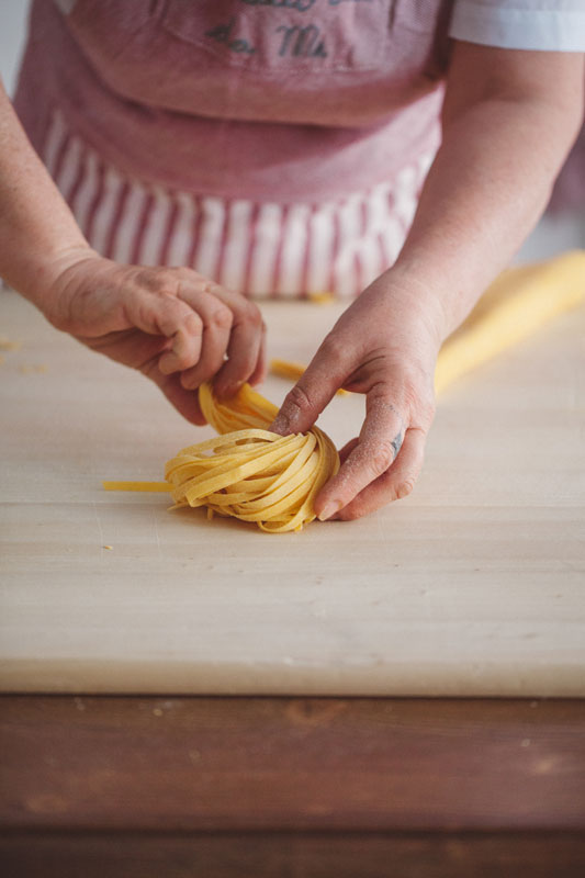 A sfoglina at Trattoria Da Me rolling tagliatelle by hand — the sfoglia pulled thin enough to see light through