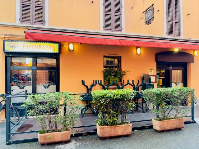 The exterior of Al Sangiovese on Vicolo del Falcone in Bologna — red awning over the entrance on a quiet side street