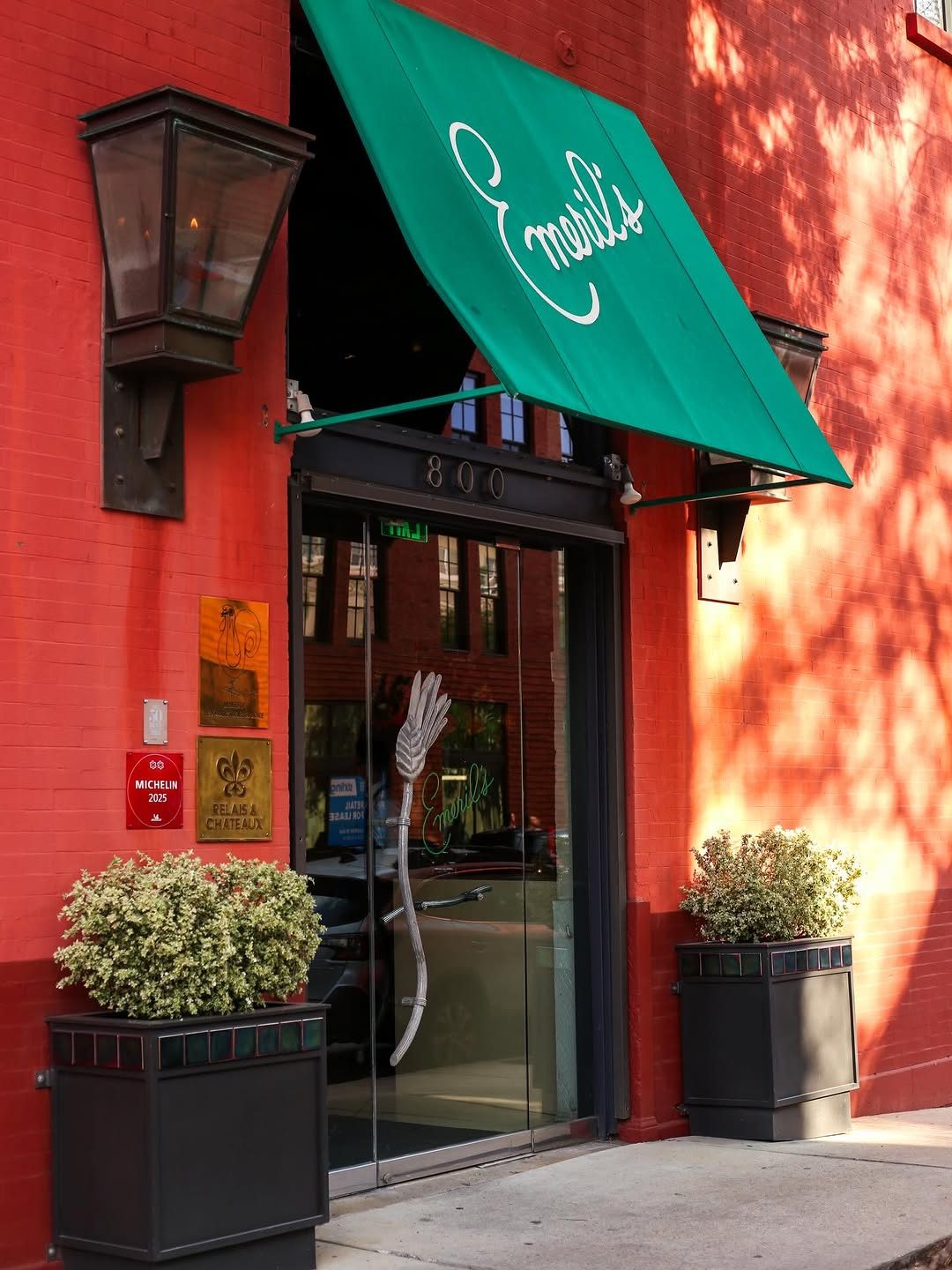 The green-awninged entrance of Emeril's at 800 Tchoupitoulas Street in New Orleans, with the restaurant's Michelin 2025 plaque and Relais & Châteaux plaque beside the door.