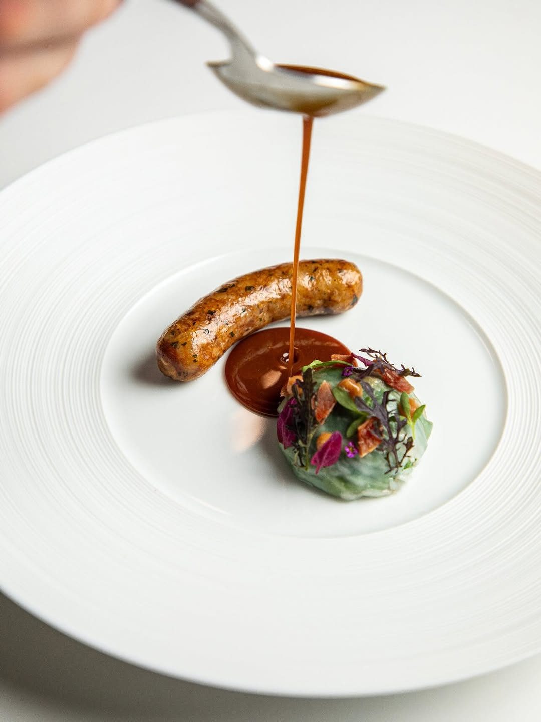 Emeril's boudin with collard greens, hamhock, and creole jus gras poured tableside.