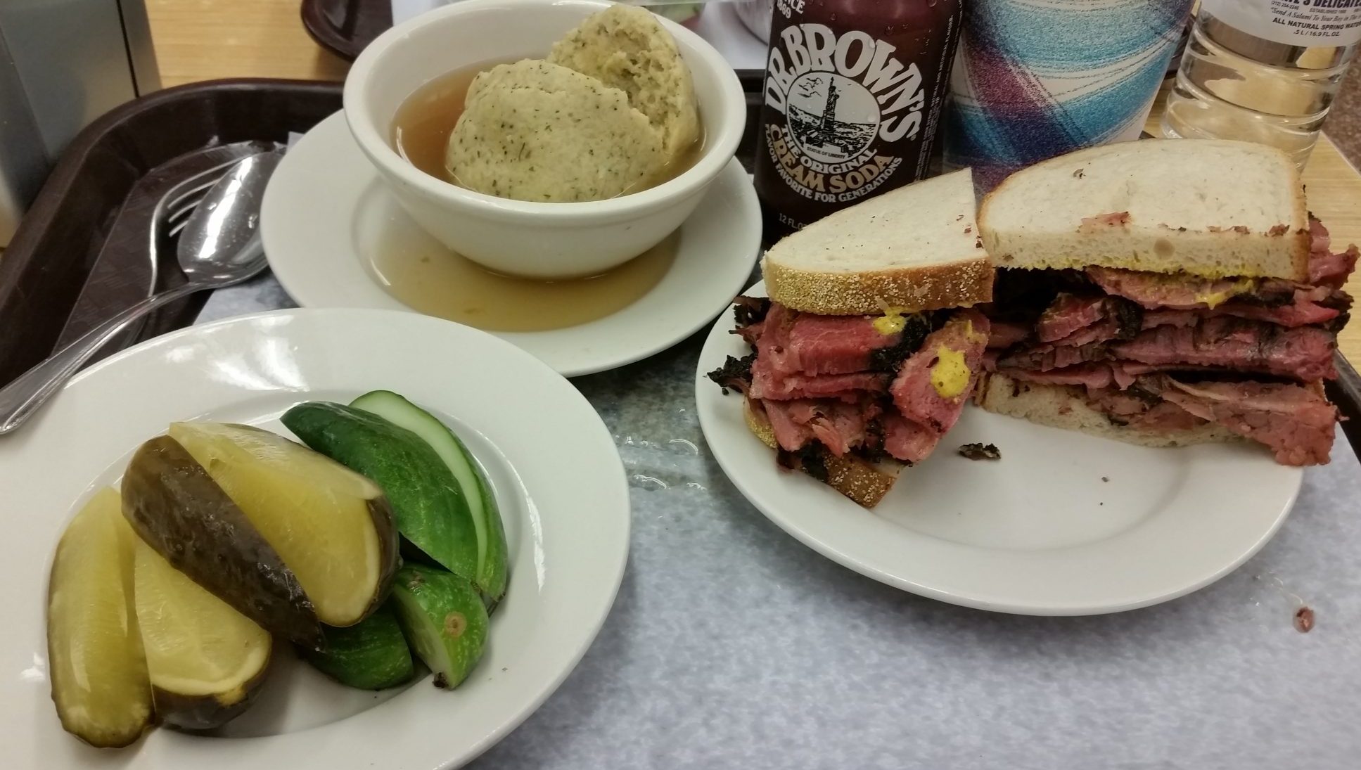 House-made pickles at Katz's Delicatessen — half-sours and full-sours on the plate, with pastrami on rye and matzo ball soup