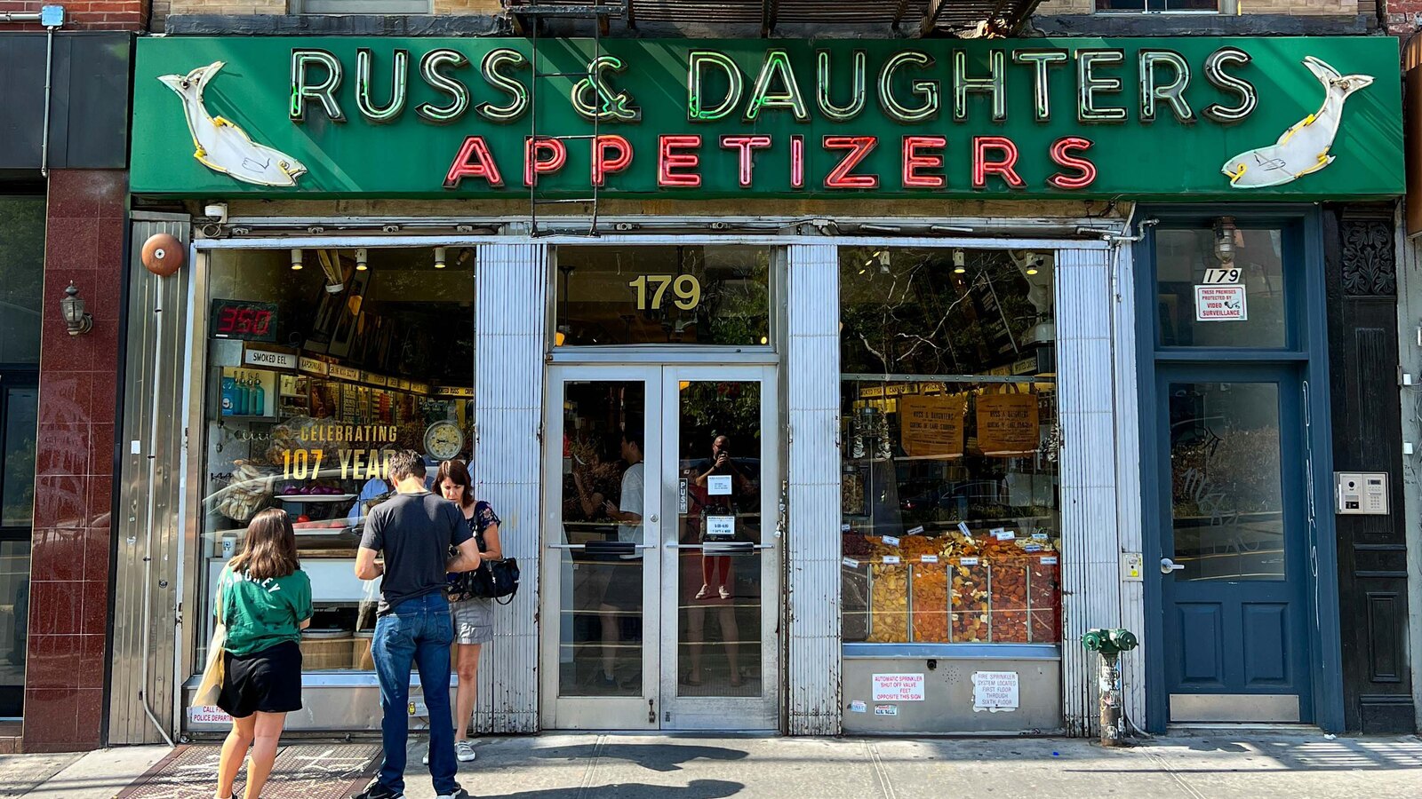 The Russ & Daughters storefront at 179 East Houston Street — the green neon RUSS & DAUGHTERS APPETIZERS sign above the shop windows