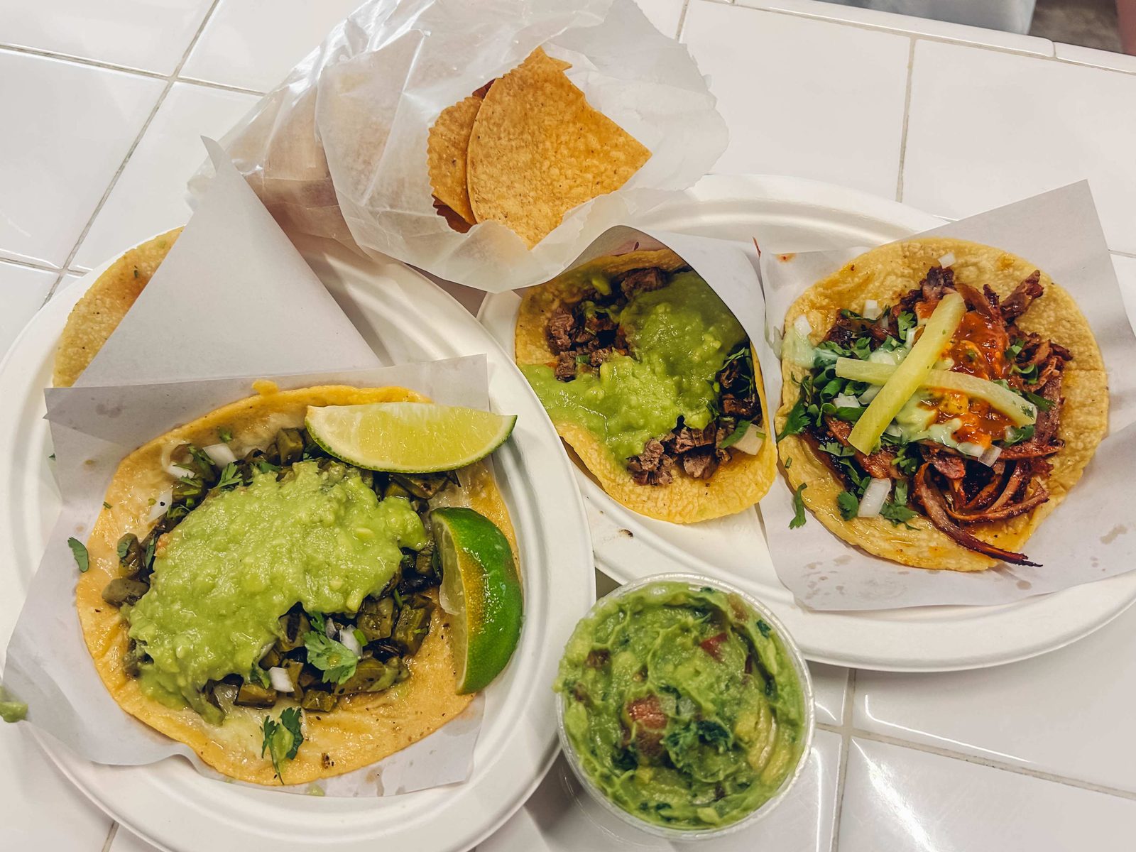 Nopal, carne asada, and adobada tacos at Los Tacos No.1: guacamole, lime, cilantro, onion, red salsa, and pineapple on handmade corn tortillas.