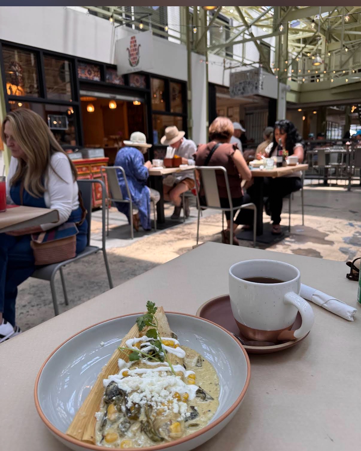 A rajas tamal with crema, queso fresco, and cilantro in front of the Casa Tamalli 505 storefront