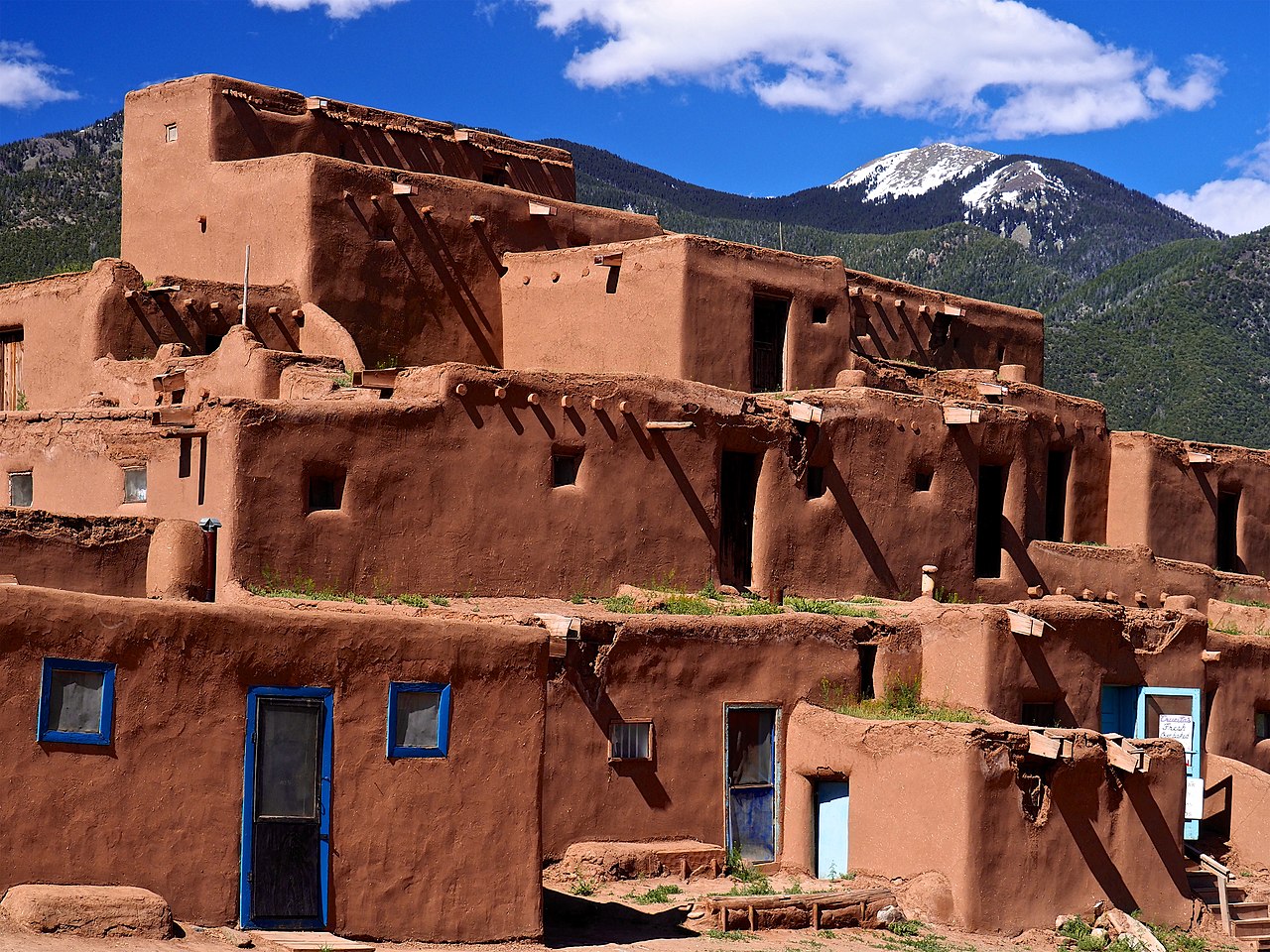 The multi-story adobe North House at Taos Pueblo with Taos Mountain behind it